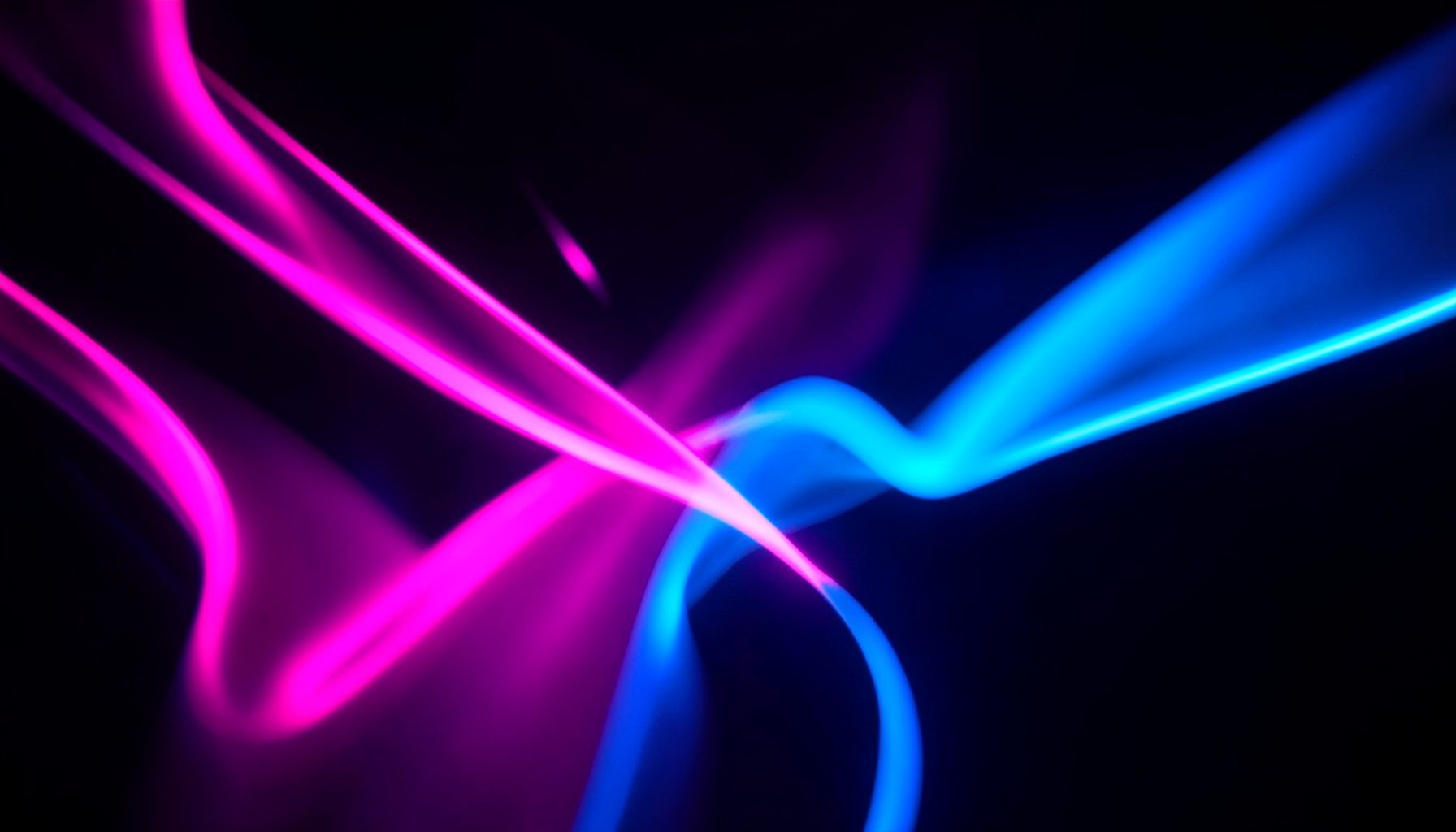 Vibrant neon pink and electric blue abstract shapes against a dark background, suggesting energy and movement